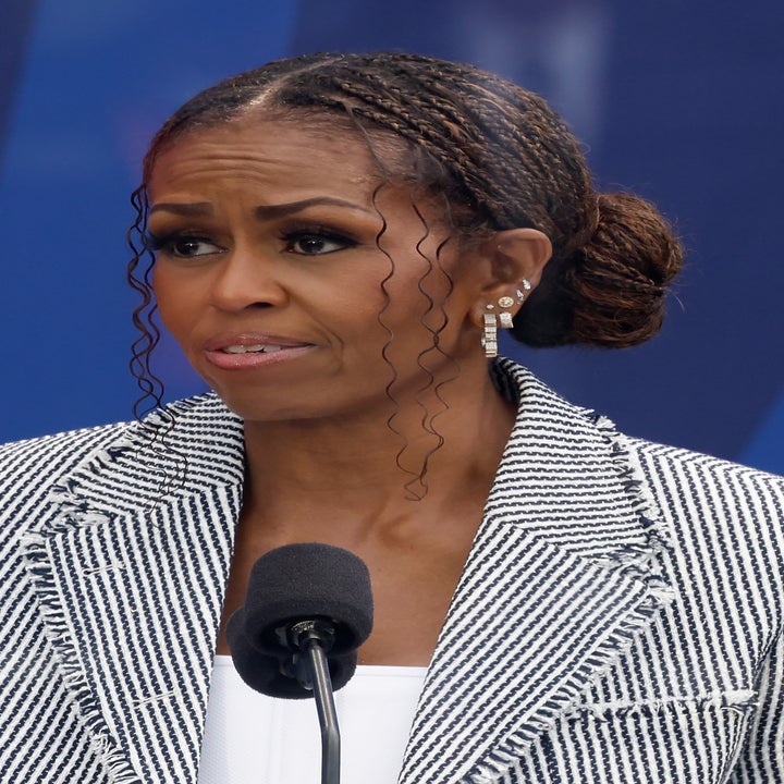 Michelle Obama snakker på et arrangement, iført en stripet blazer og elegant flettet frisyre, med en mikrofon foran seg