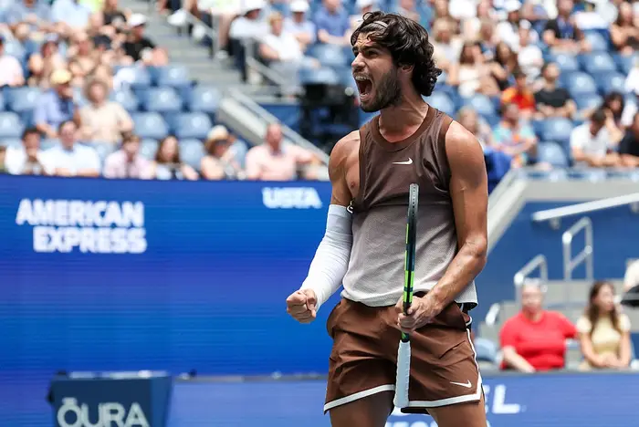 Tennisspiller i sporty antrekk feirer en seier på banen, og knytter lidenskapelig neve med et jublende publikum i bakgrunnen