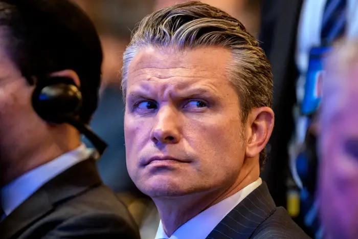 Person i forretningsdress med et bekymret uttrykk, iført øretelefon, sannsynligvis på et arrangement eller sammenkomst