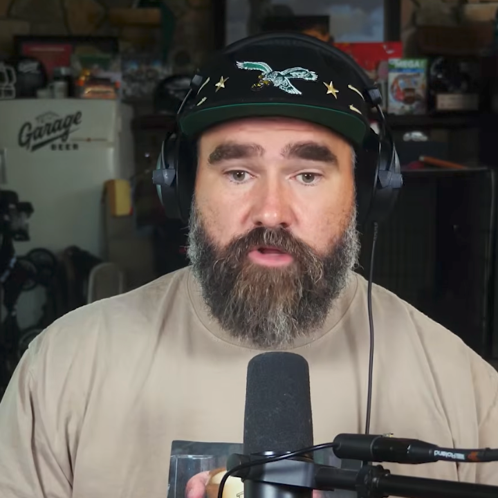 To menn med hodetelefoner og mikrofoner dukker opp i en podcast-videosamtale. Den ene er skjeggete og seriøs, mens den andre smiler