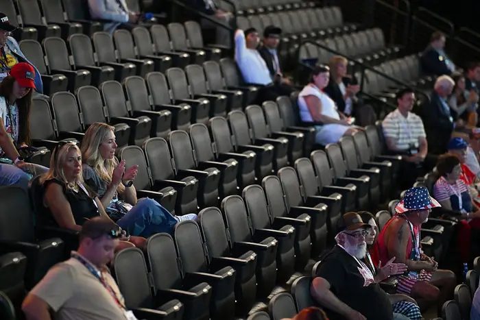 Sparsomt publikum sitter på rader i et stort auditorium, noen klappende, uformelle antrekk