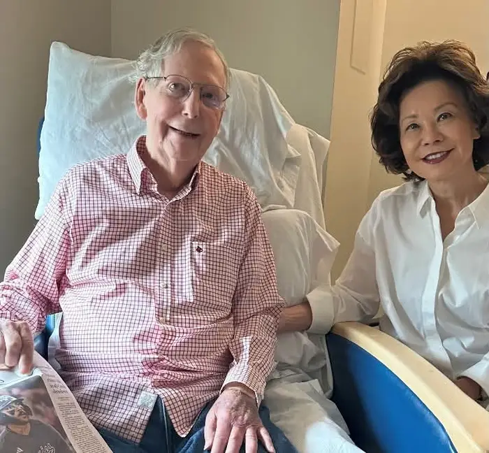 McConnell i en sykehusseng med en avis med kona poserte ved siden av ham