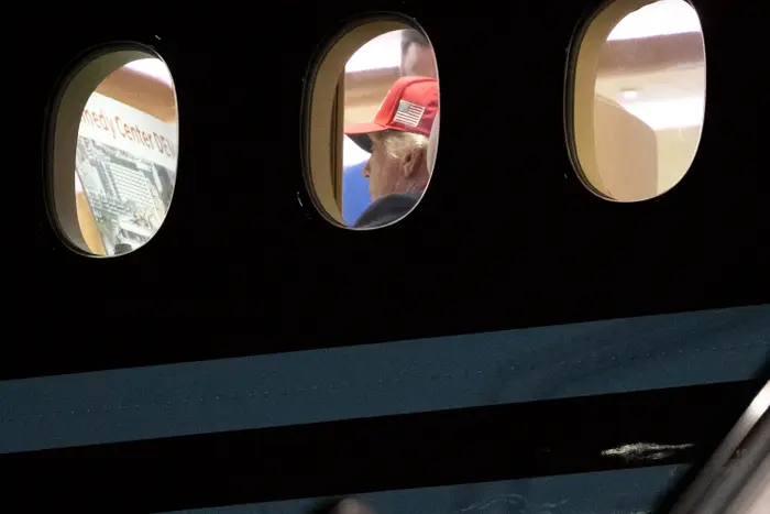 Person i en rød lue med et amerikansk flagg sees gjennom flyvinduer