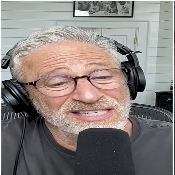 Mann med briller og hodetelefoner snakker i en mikrofon under en podcast
