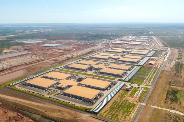Luftfoto av et stort industrikompleks med flere bygninger omgitt av jorder og veier i et enormt landskap