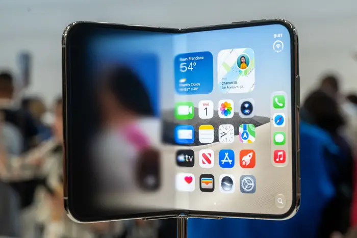 En sammenleggbar smarttelefon som viser apper på skjermen, vist i åpen posisjon ved et teknisk arrangement, med uskarp bakgrunn