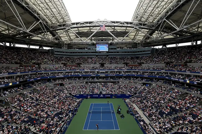 Bredt bilde av en fullsatt tennisstadion under en kamp, sett ovenfra, fremhever publikum og lukket arenastruktur