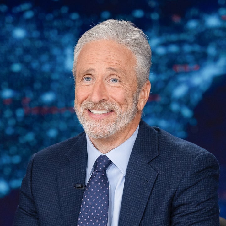 En person i dress sitter ved et skrivebord på et TV-apparat med «The Daily Show»-logoen bak seg
