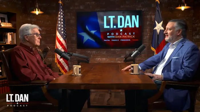 To menn sitter ved et podcastbord med mikrofoner. Et bakteppe viser en logo: "LT. DAN Podcast med Dan Patrick." Amerikansk flagg synlig