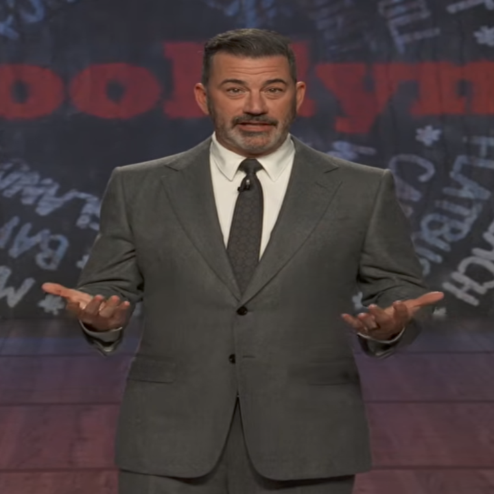 Jimmy Kimmel i en grå dress gester på scenen