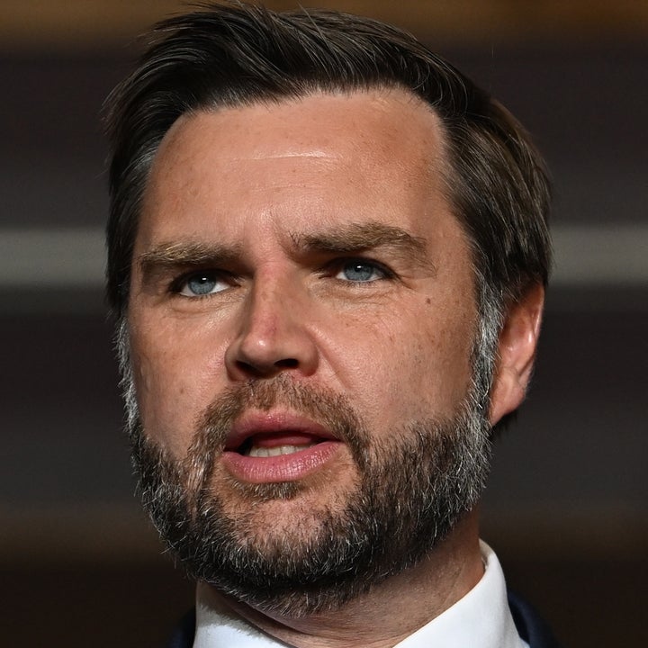 En mann i dress taler ved et podium med offisielt segl; han gestikulerer med én hånd, noe som indikerer en engasjert tale eller presentasjon