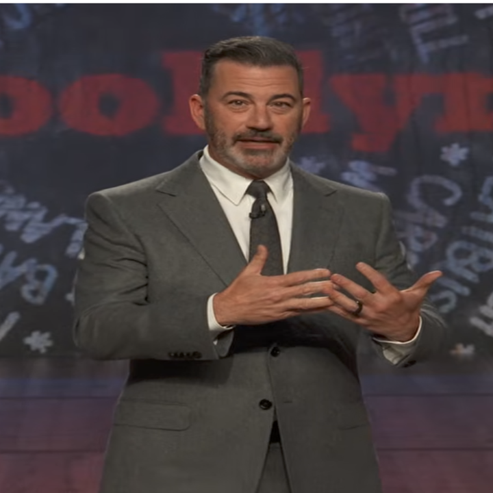 Jimmy Kimmel i en grå dress gester på scenen